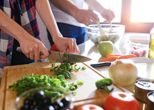 Close-up of young couple cooking together in the kitchen at home.